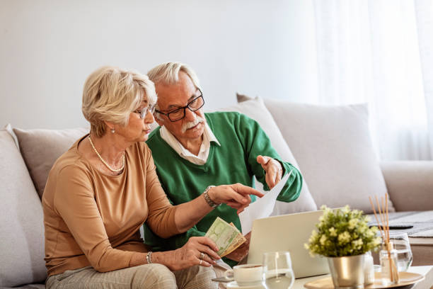 istock Senior couple counting bills at home. 1287052385