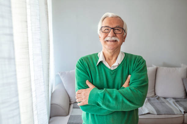 Portrait elderly man at home Close-up portrait of happy senior man looking at camera. Portrait elderly man at home. Elderly Man Smiling Face Expression Concept. Happy smiling 70 year old elder senior man portrait mid length hair stock pictures, royalty-free photos & images