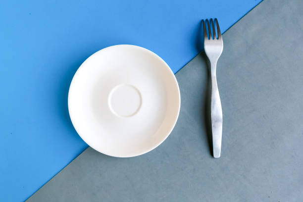 istock Empty plate and fork on grey and blue background. Copy space for the text. Minimal concept 1287058505