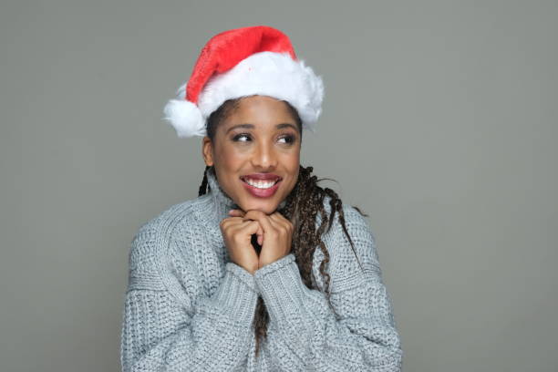 портрет очень счастливой молодой женщины с рождественской шляпой санта, надеясь и желая, глядя в сторону - braided women african descent winter стоковые фото и изображения