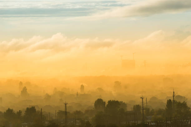 Sunset in city with fog, mist and orange sunset clouds