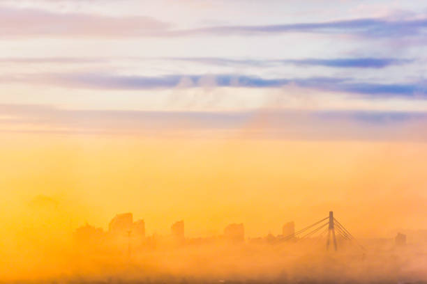 River IJssel covered in a blanket of mist seen from above at the Hanzeboog train bridge during a fall morning near the river IJssel in Overijssel. The treetops are popping out over the thick fog with some of the trees starting to change color during the annual autumn season. The fog is giving the landscape a mystical atmosphere.