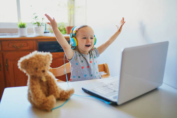 toddler girl wearing eraphones with laptop - baby animals audio imagens e fotografias de stock