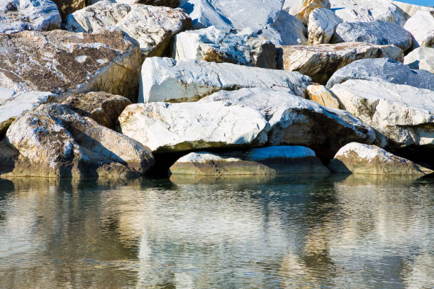 istock Stone breakwater rocks are reflected in the water 1287064029