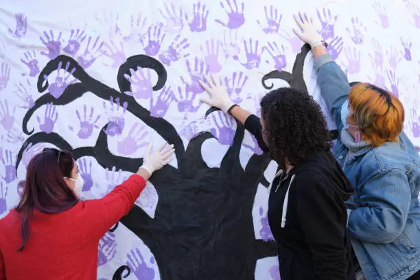 Three women participating in the International Day for the Elimination of Violence against Women participatory mural. 25 november.