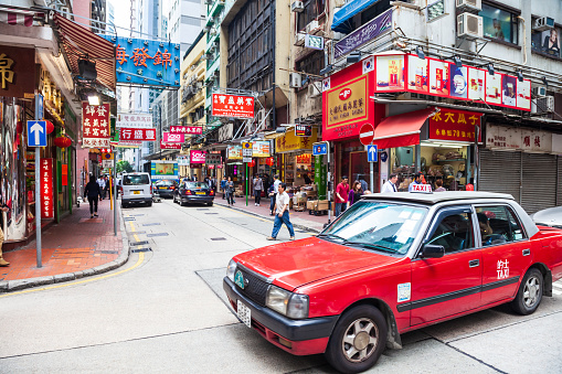 HONG KONG - MARCH 19, 2013:  Red taxi on a busy street. Red taxi is a symbol of Hong Kong city in China.