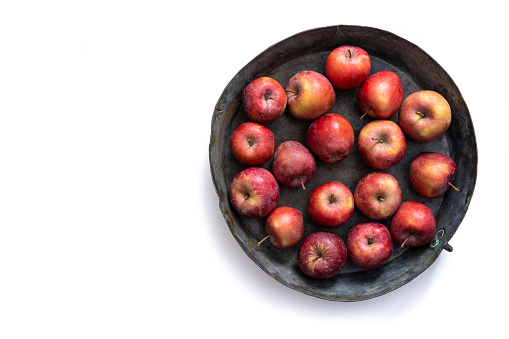 Red organic apples in a vintage round tray isolated on white background
