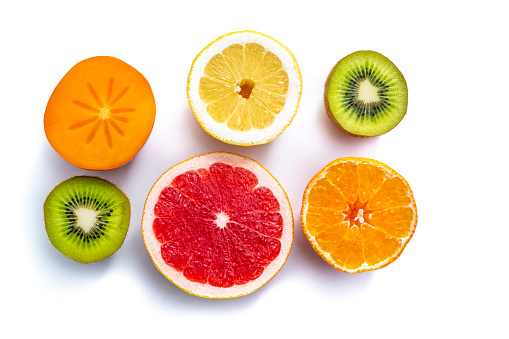 cut half fruits persimmon, lemons,kiwi, grapefruit, tangerine citrus isolated on white background in a row