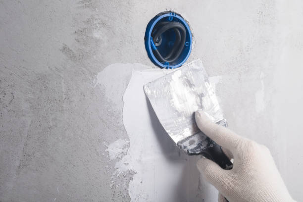 istock plasterer seals the wiring in the wall from the new socket with a spatula 1287071625