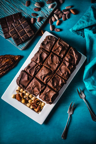 шоколадный торт brownie на бирюзовом фоне с орехами - cooked still life close up nut стоковые фото и изображения