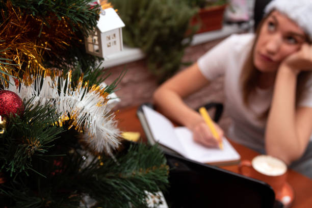 A girl in a new year's cap paints her goals in a notebook with a rework. Selective focus.