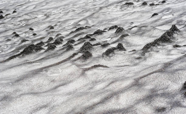 istock Abstract dirty black sand waves on white snow. 1287073278