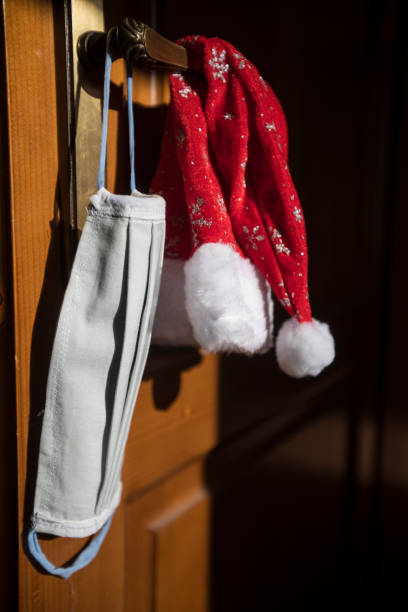 istock Santa Hat and Protective Face Mask Hanging on Door Handle 1287073524