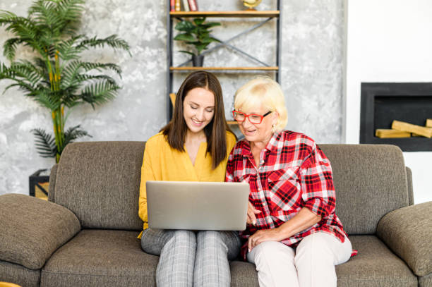 femmes jeunes et aînées avec un ordinateur portatif - grandparent senior adult child reading photos et images de collection