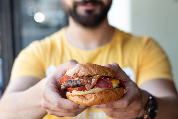 istock young holding in male hands fast food burger 1287076677