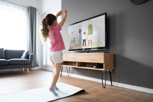 istock Kid Doing Online TV Fitness Exercise 1287079452
