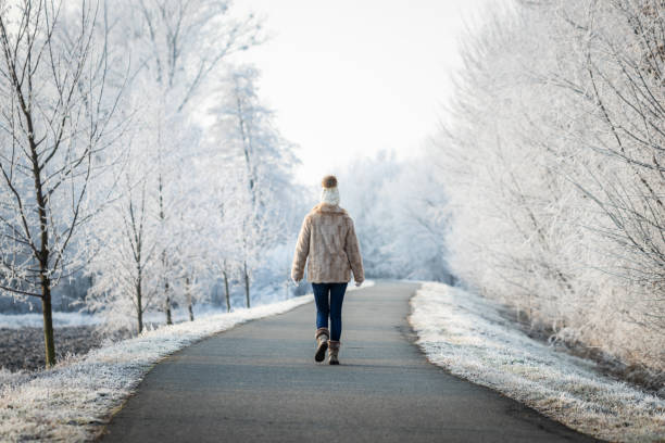 istock Woman walking on footpath in park at winter. 1287080339