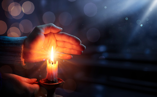 Hands Holding Candlestick With Shining Flame And Bokeh Lights