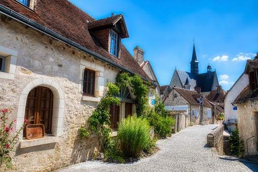 Street in the beautiful village of Montresor, Loire, France, with St John the Baptist Collegiate Church