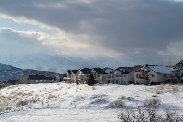istock Homes on snowy terrain ovelooking Wasatch Mountain peak and dark overcast sky 1287085422