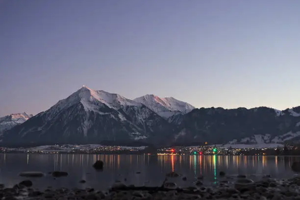 Lake Thun and the mountain Niesen during twilight with reflection of little village lights in the lake.