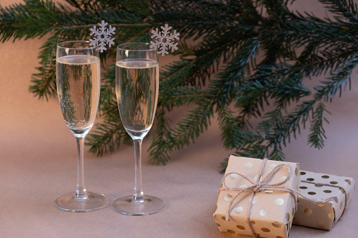 two glasses of champagne and gifts lie on the New Year's table on a beige background