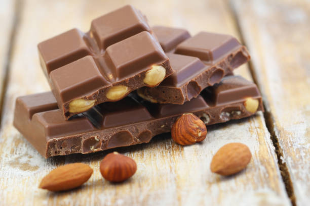 istock Milk chocolate pieces with whole hazelnuts and almonds on rustic wooden surface 1287090597