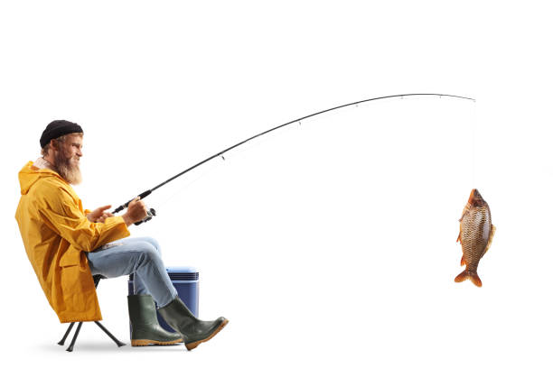 Full length profile shot of a young fisherman sitting on a chair and catching fish isolated on white background Full length profile shot of a young fisherman sitting on a chair and catching fish isolated on white background fishing rod photos stock pictures, royalty-free photos & images