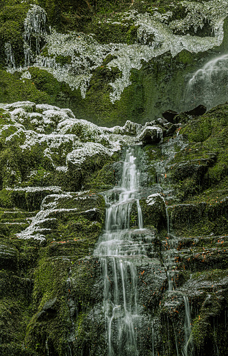 Late autumn close up of water flowing down Proxy Falls surrounded by frosty rocks