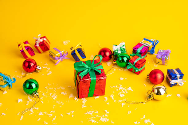 istock Gift box with a Christmas present on a yellow background, among the New Year's decorations 1287092020