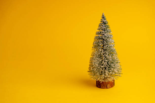istock Christmas tree in the snow on a yellow background. Copy space. Christmas decorations 1287092255