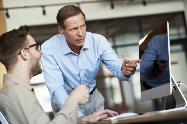 istock Two male colleagues looking at computer monitor and discussing something while working together at office 1287096303