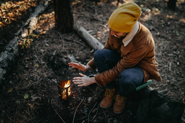 istock Man warming himself up by fire while camping on autumn day in forest 1287100435