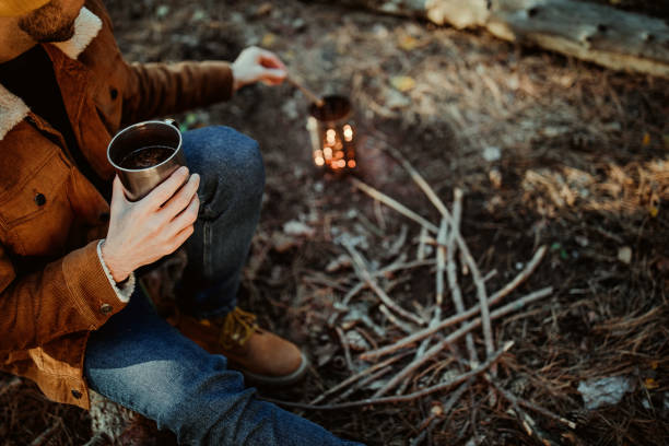istock Man warming himself up by fire while camping on autumn day in forest 1287100469