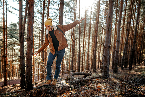 Young man enjoying hiking in forest on sunny autumn day