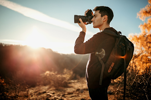 Young photographer hiking on mountain and photographing nature