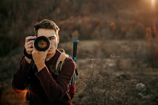 Young photographer hiking on mountain and photographing nature