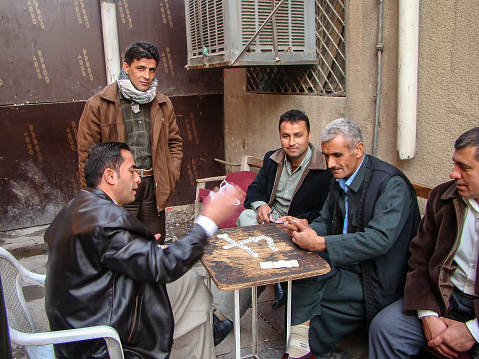 Group of men meetin in basar for gambling, backgammon or dealing cards, old town of Arbil, Northern Iraq