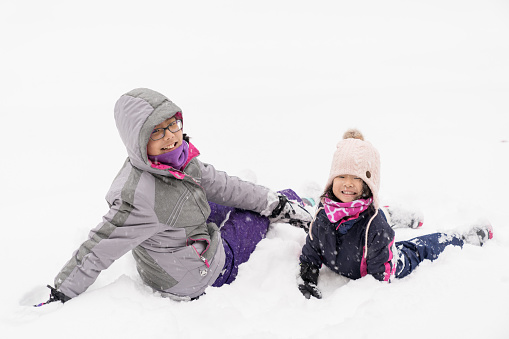 Two little Asian children playing in snow during winter