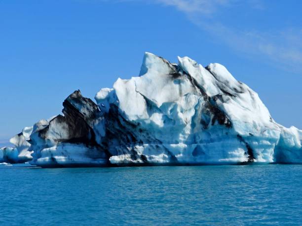 iceberg in glacier lagoon jokulsarlon, iceland. gigantic awesome iceberg in glacial lake. majestic snow blue ice floe on calm water. spectacular icelandic winter landscape. - ice floe imagens e fotografias de stock