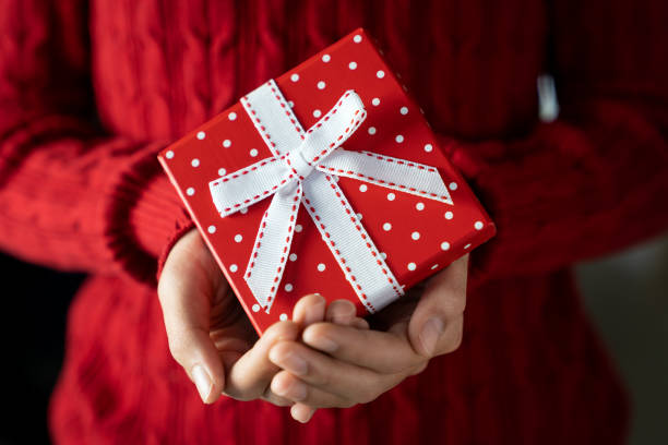 istock Young female hands holding gift box with ribbon 1287107922