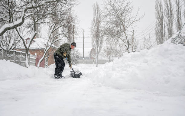 Man with a shovel cleans the track from the snow elderly man with a shovel in his hands clears the street after a heavy snowfall. Man at seasonal work deep snow stock pictures, royalty-free photos & images