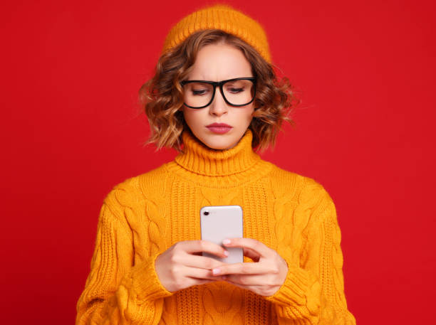 istock thoughtful young female blogger  exchanges messages with friends using a smartphone on a bright red background 1287109172