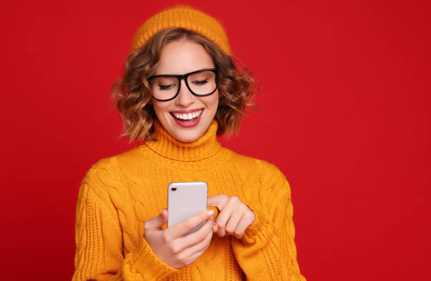 istock cheerful young female blogger  exchanges messages with friends using a smartphone on a bright red background 1287110138