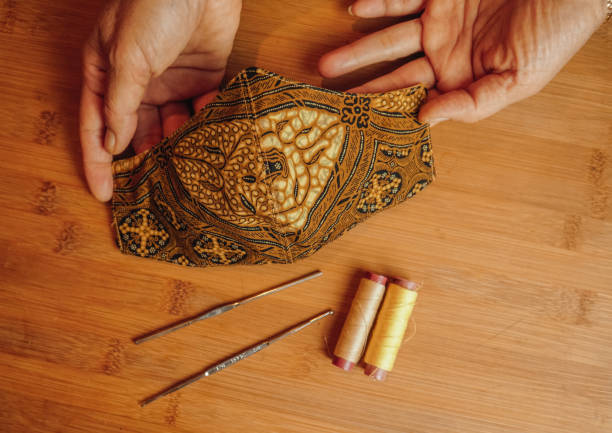istock Cloth mask with Indonesian Batik pattern held by a woman's hand 1287110821