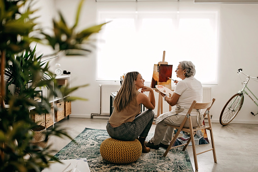 Senior women and her granddaughter painting on canvas
