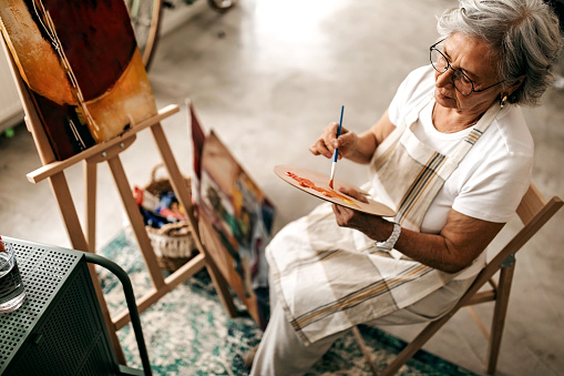 Senior women using acrylic colour to pain on canvas