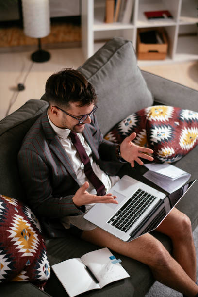 jovem usando o laptop tendo chamada de vídeo. - relaxation working humor sofa - fotografias e filmes do acervo