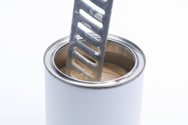 A man stirring white paint in can on white background. Renovation concept.