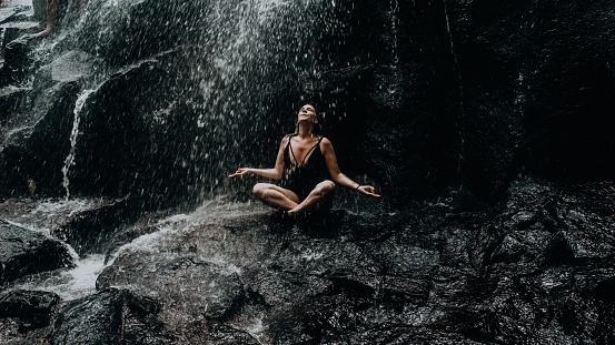relaxed girl under a waterfall in Bali